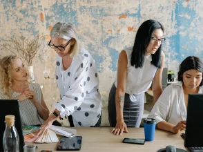 Team collaborating on brand and marketing planning using laptops and design samples in a creative workspace.