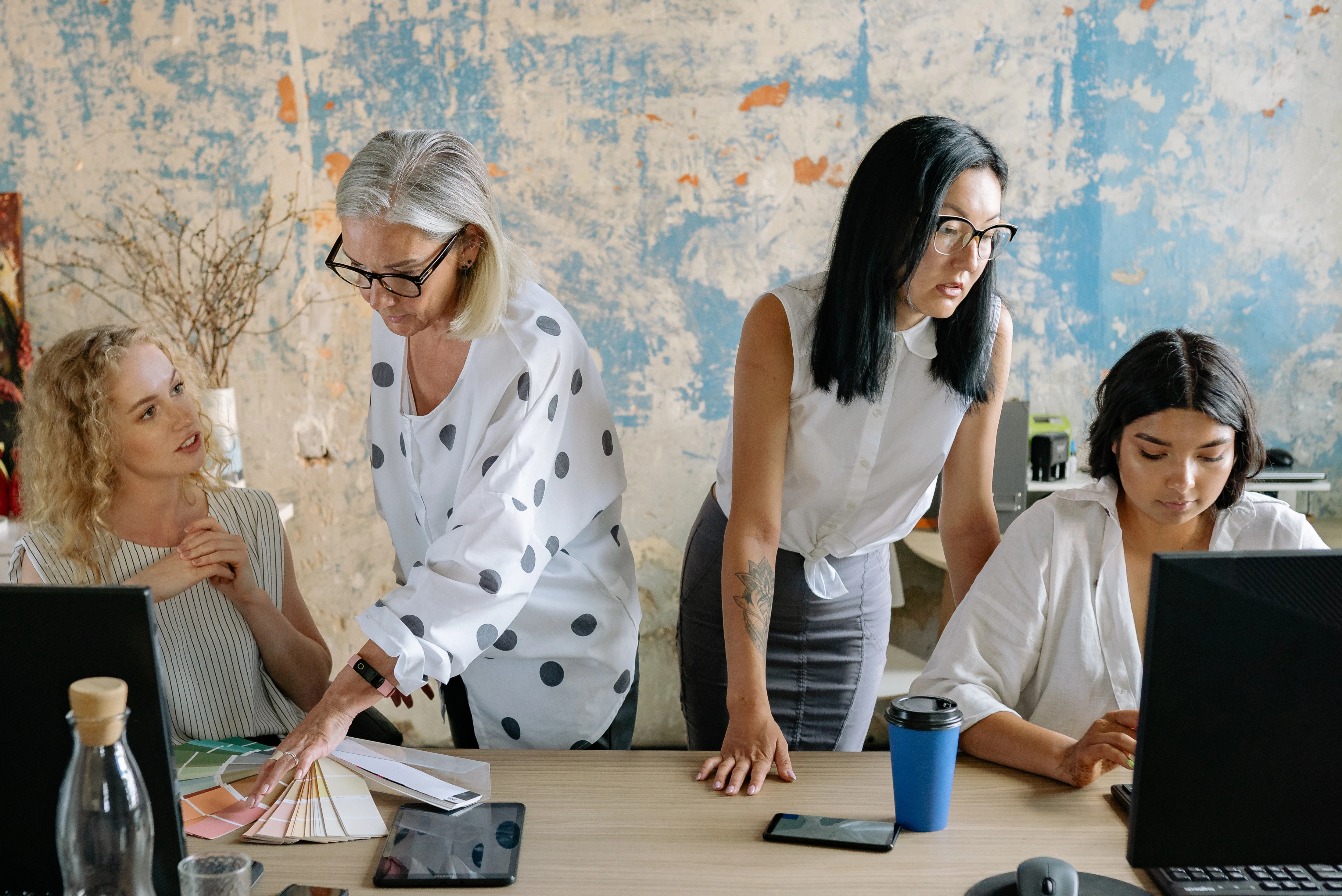 Team collaborating on brand and marketing planning using laptops and design samples in a creative workspace.