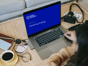 Laptop displaying a Knowcrunch marketing strategy fundamentals course on a desk with work accessories.