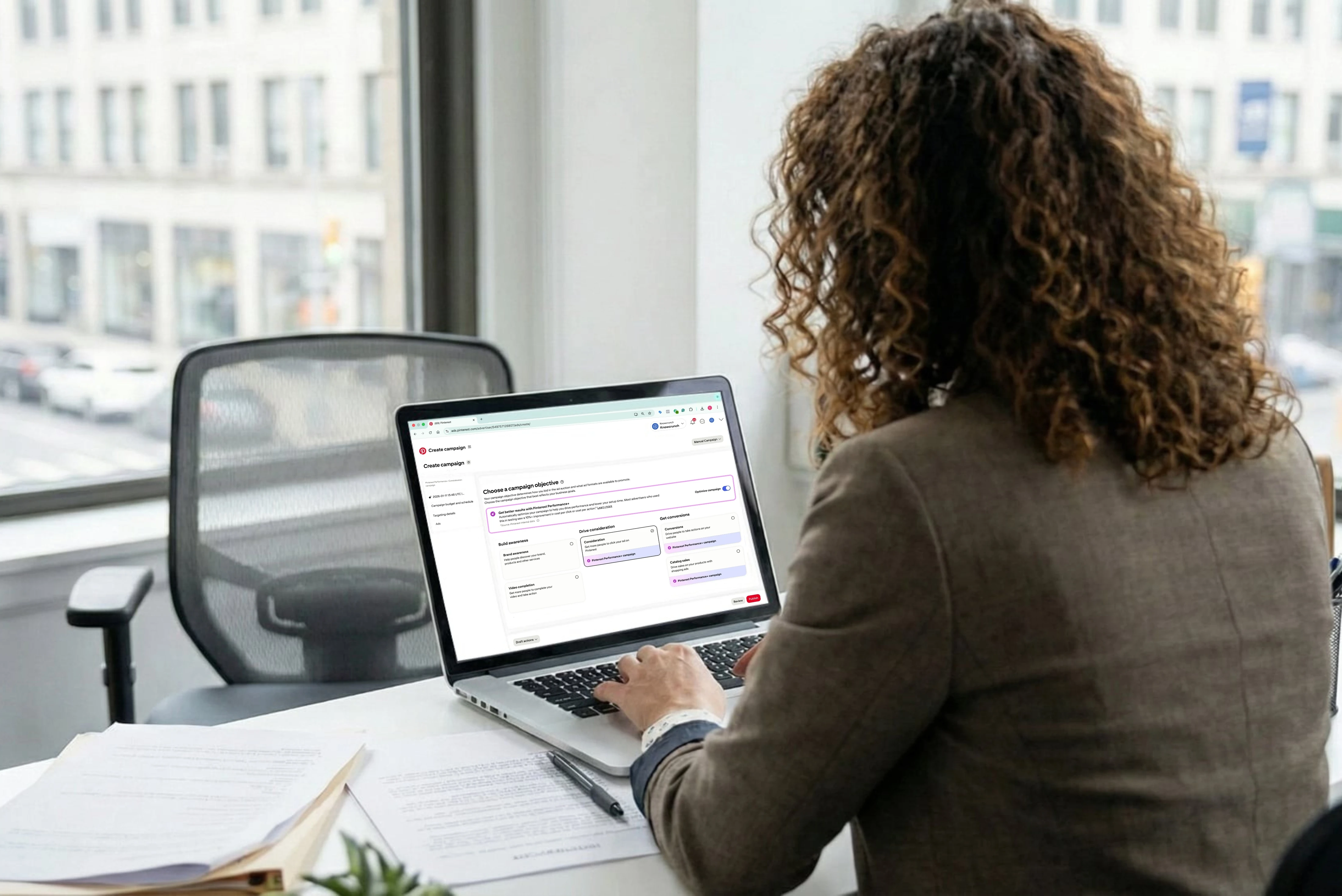 Professional working on a laptop setting up a digital advertising campaign on Pinterest in an office.