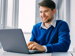 Professional working confidently on a laptop in a bright office environment.